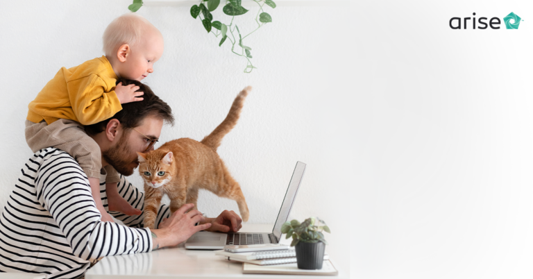 Father working with son on his head and a cat in front of his face.
