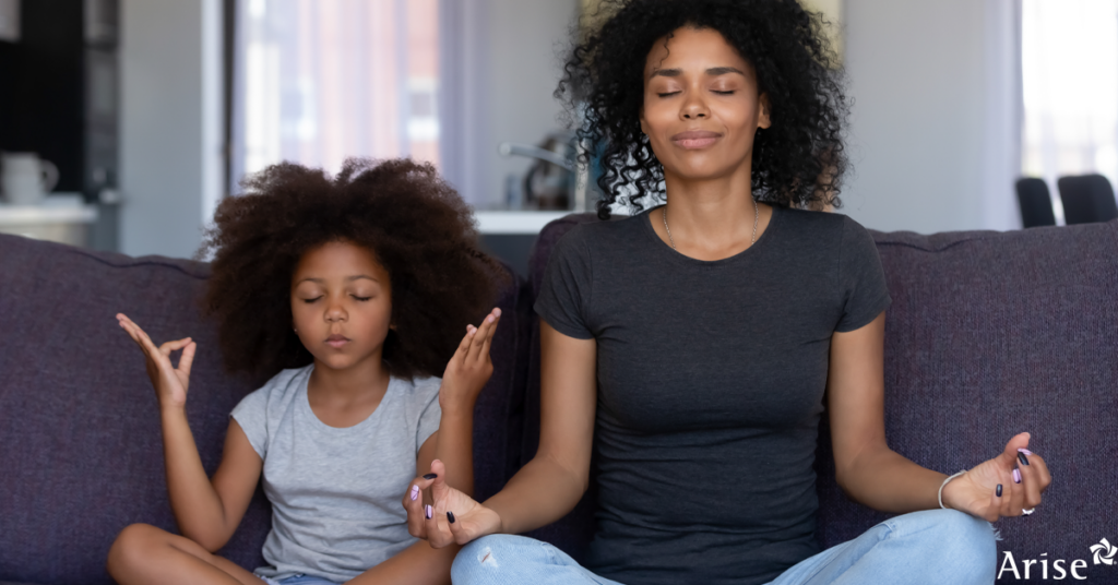 Woman and child meditating on a couch.