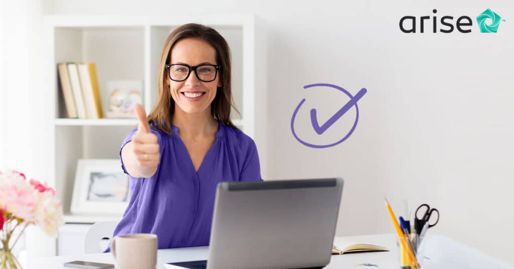 Woman sitting at a desk with a computer, holding a thumbs up.