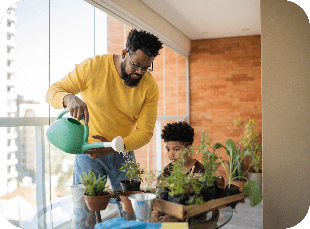 Smiling man and child watering plants.