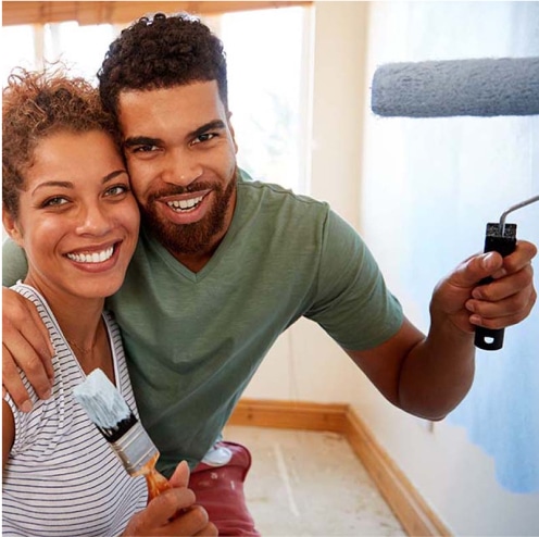 Smiling man and woman holding paint brushes.