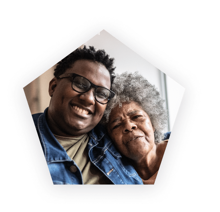 Smiling man wearing glasses hugging an older woman.