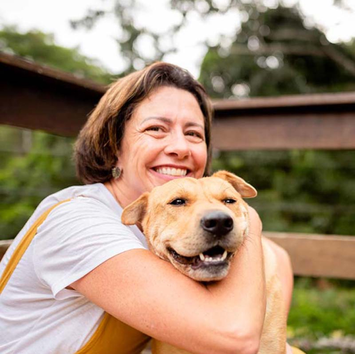 Smiling woman hugs a dog.