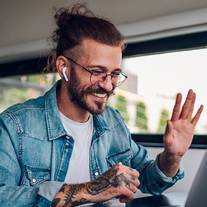 Smiling man waving and wearing ear pods.