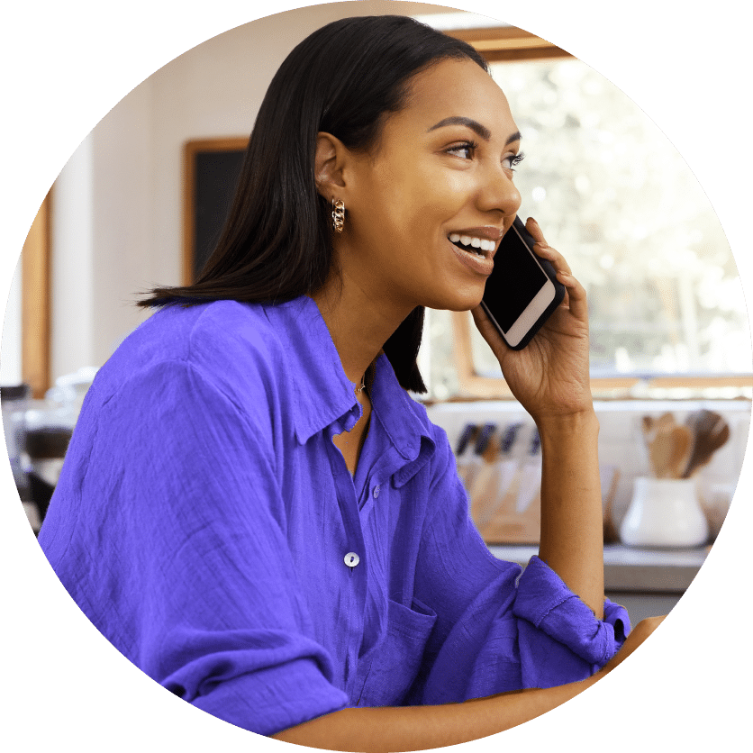 Smiling woman wearing a purple shirt and talking on a phone.