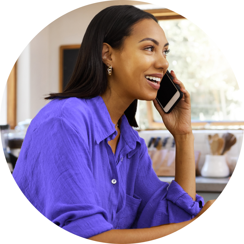 Smiling woman wearing a purple shirt and talking on a phone.