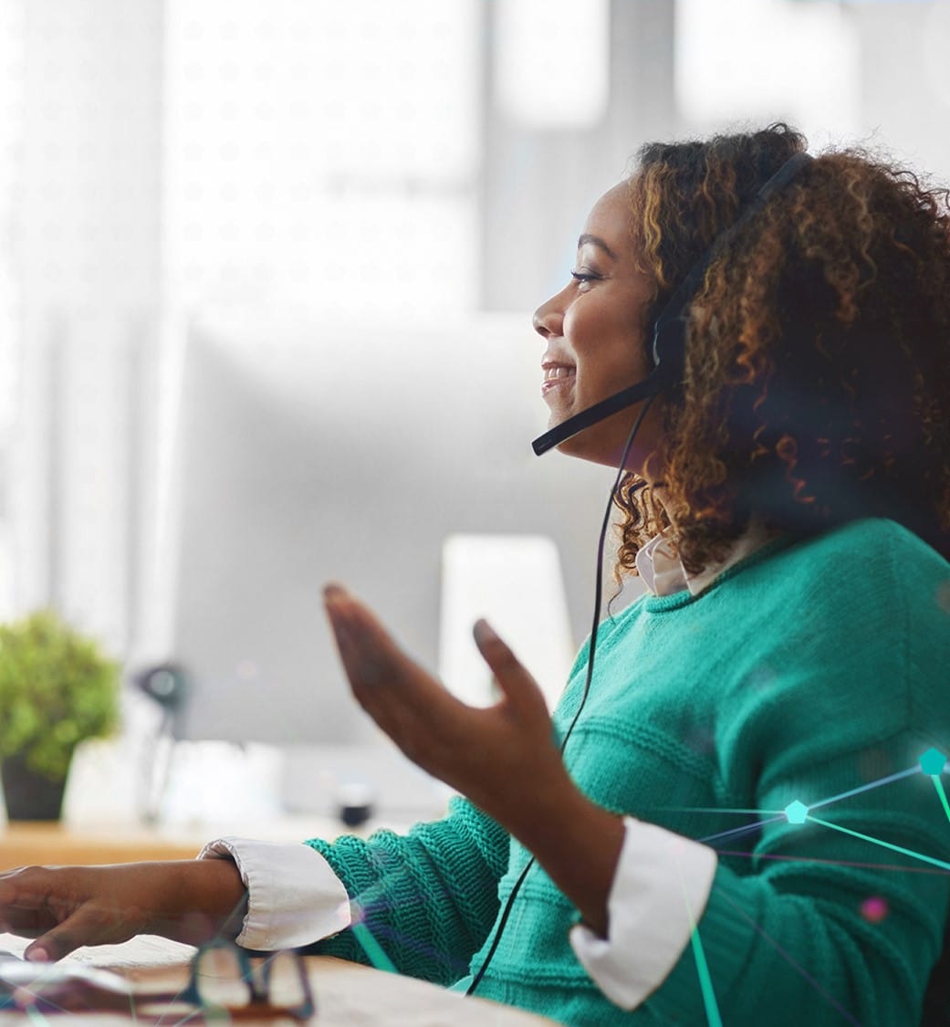 Smiling woman wearing headset and working on a computer.