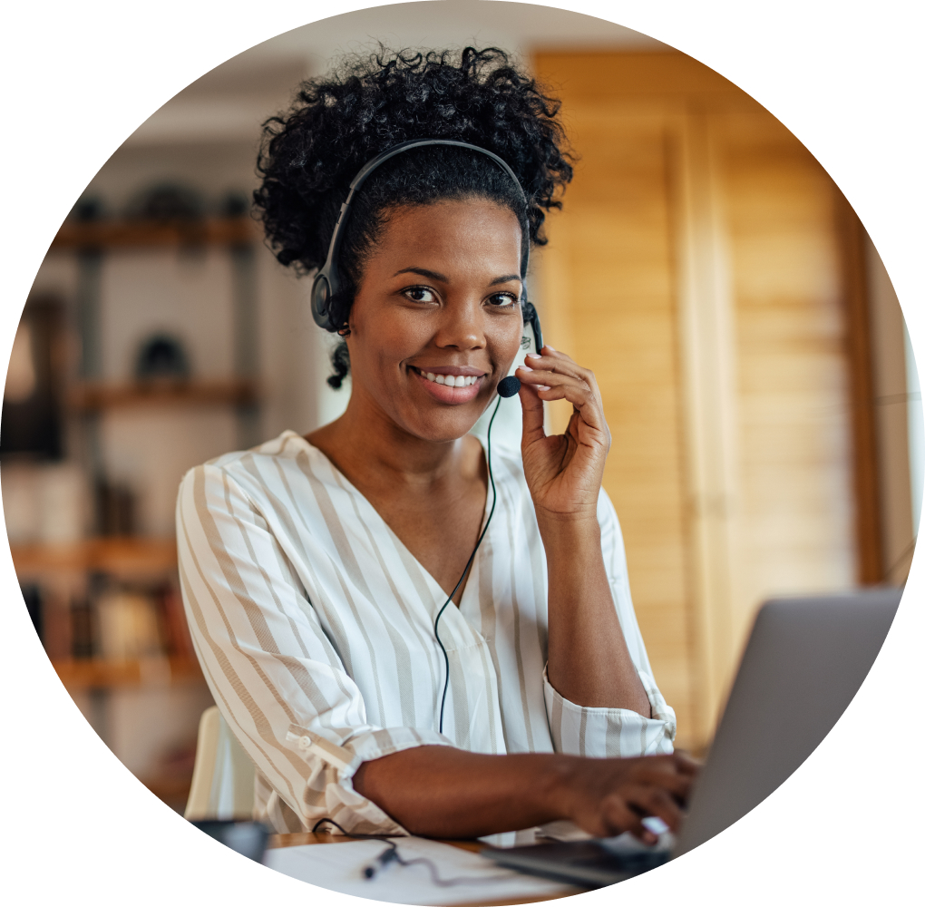 Smiling woman wearing headset and working on a computer.