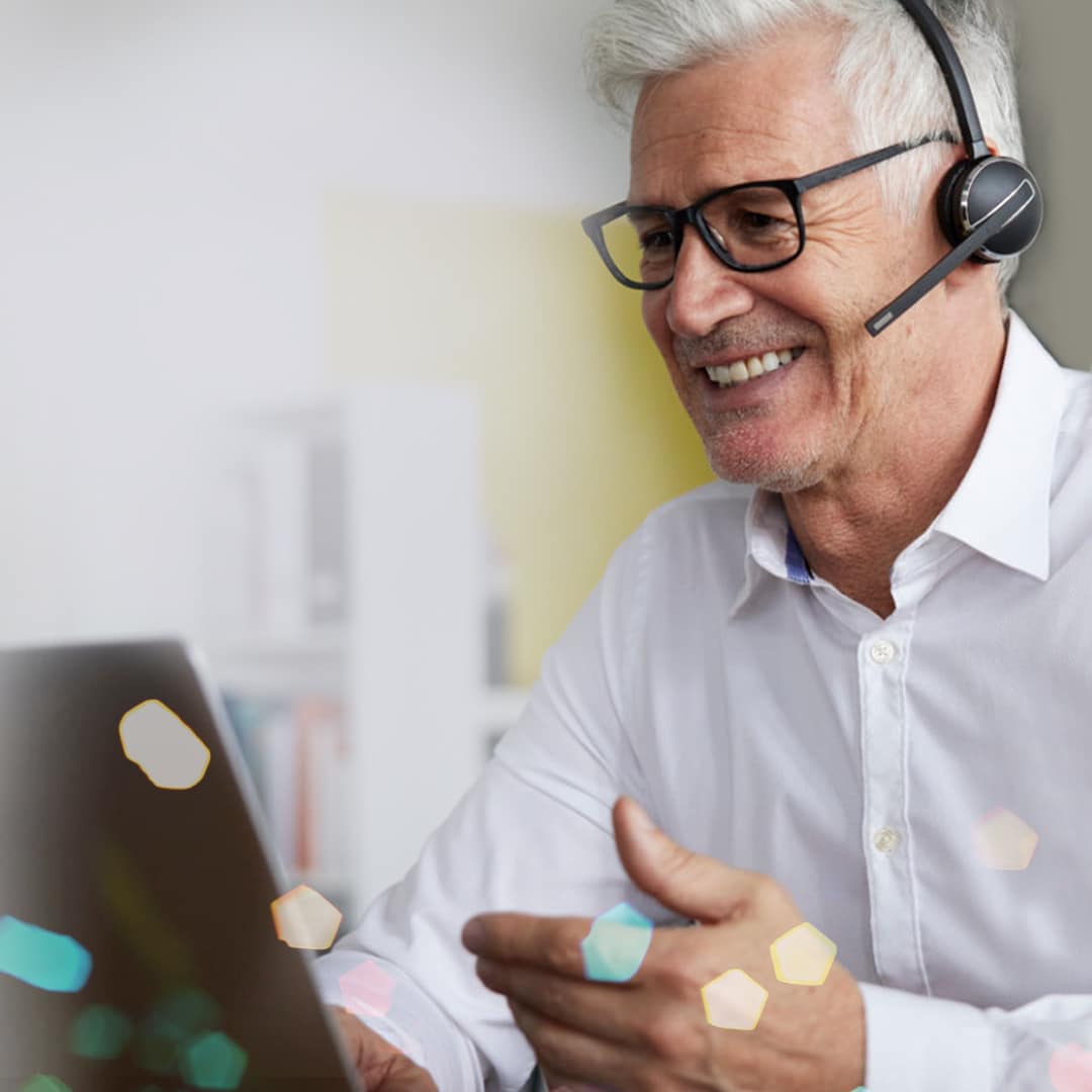 Smiling man wearing headset and working on a computer.