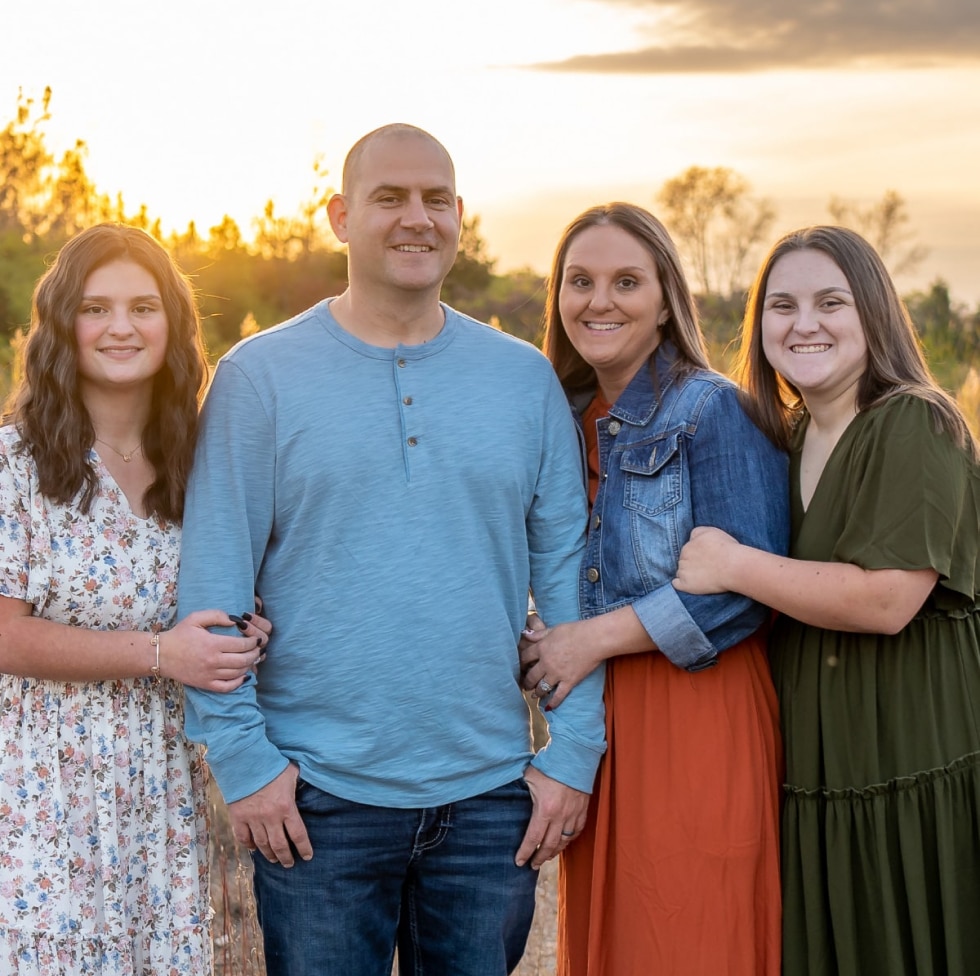 Smiling family in front of sunset.