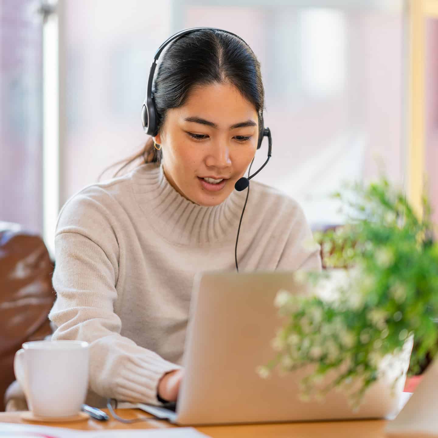 Smiling woman wearing headset working on a computer.